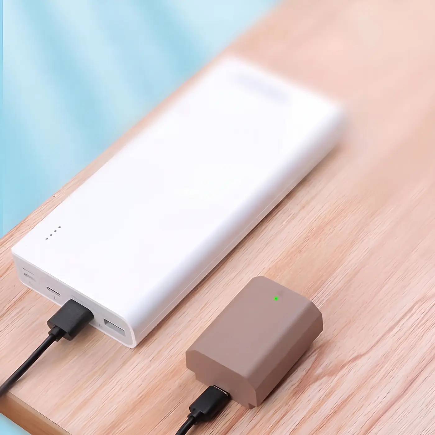 Аккумулятор Kingma NP-FZ100 заряжается от павербанка по кабелю USB-C на деревянном столе