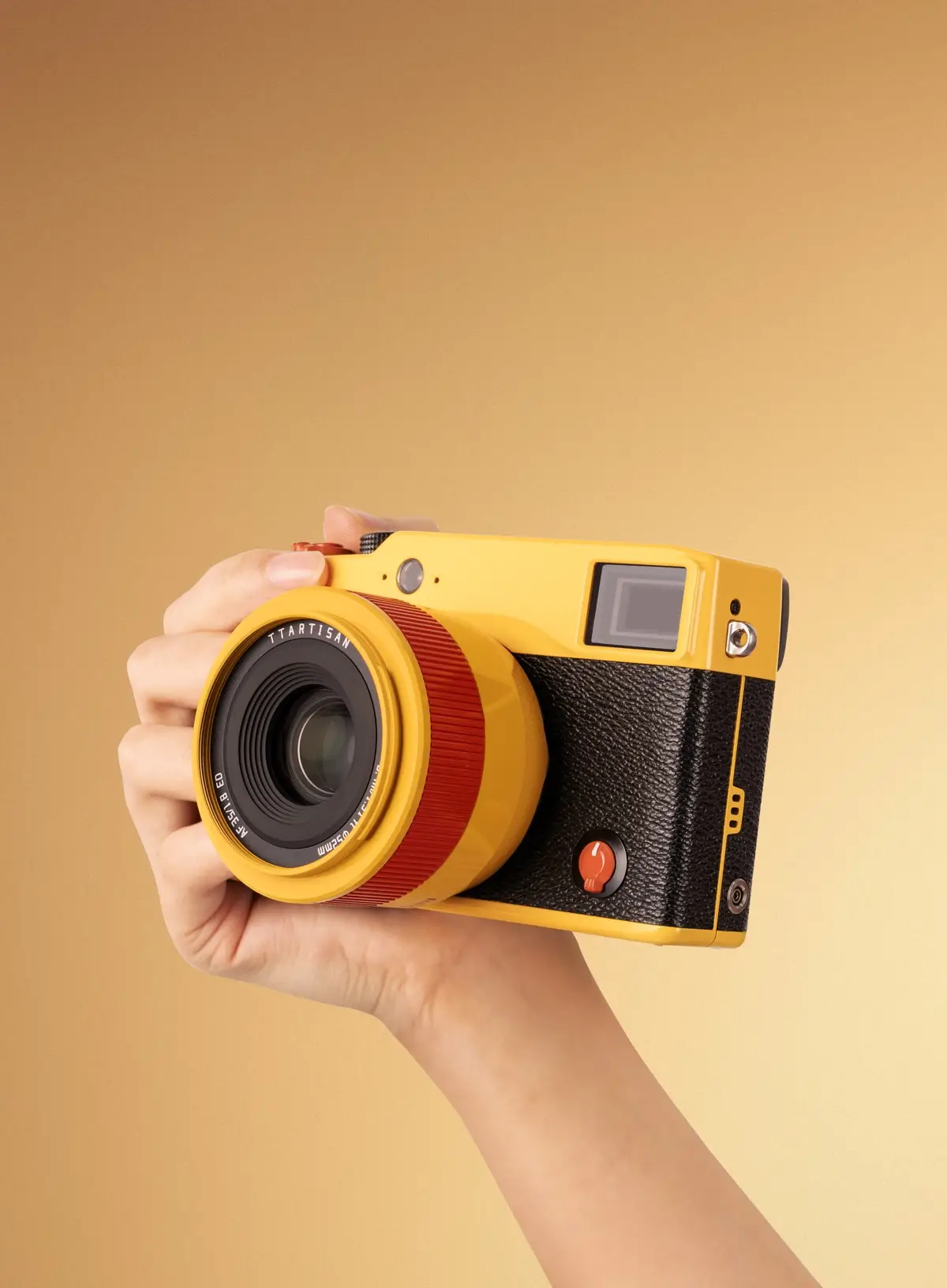 Жёлтая камера с объективом TTArtisan AF 35 мм F1.8 II Orange Pop в руке