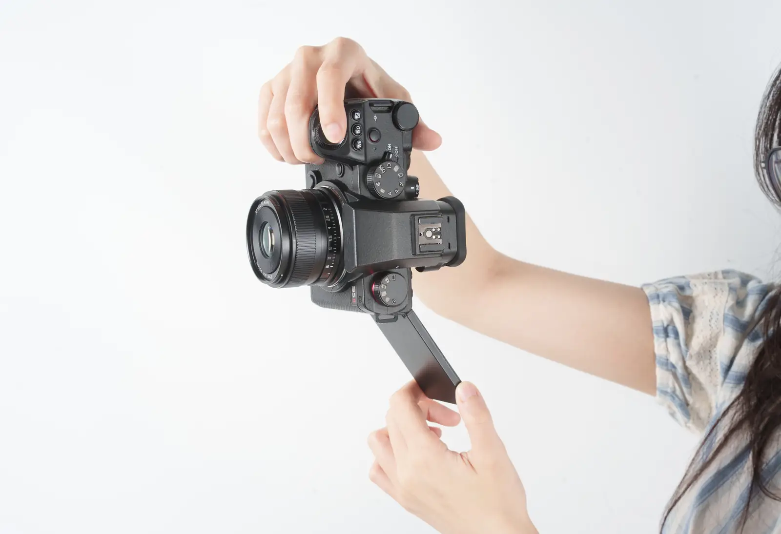 Камера Panasonic Lumix с объективом TTArtisan AF 40 мм F2 и откинутым экраном в руках — влог