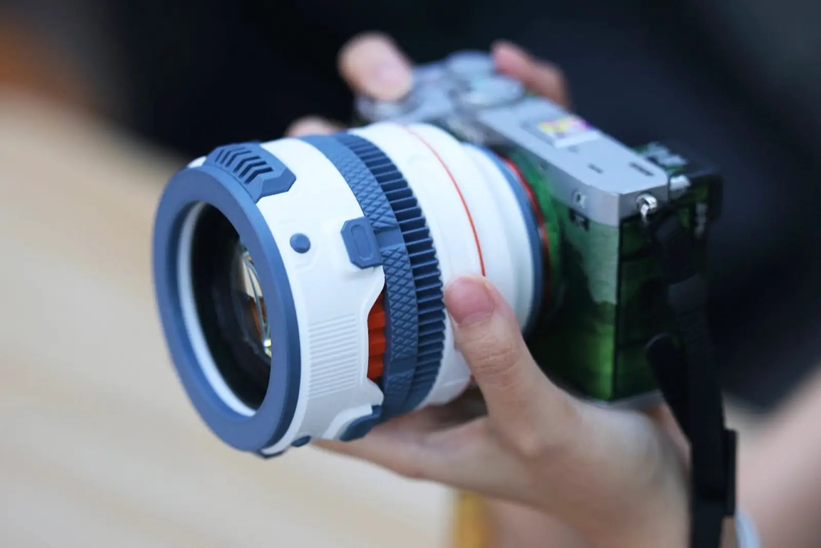 Объектив TTArtisan AF 85 мм F1.8 Neo в напечатанной на 3D-принтере бело-синей оболочке на камере в руках