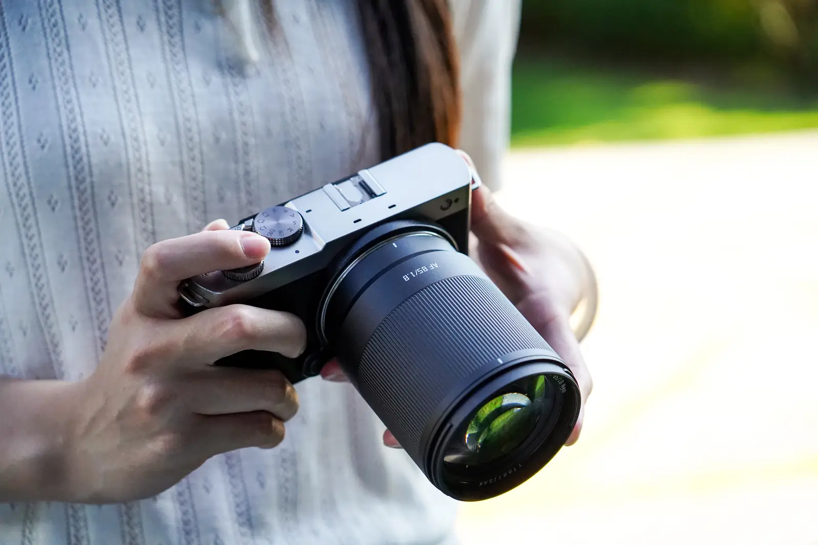 Камера Panasonic Lumix S9 с объективом TTArtisan AF 85 мм F1.8 Neo в руках фотографа на природе