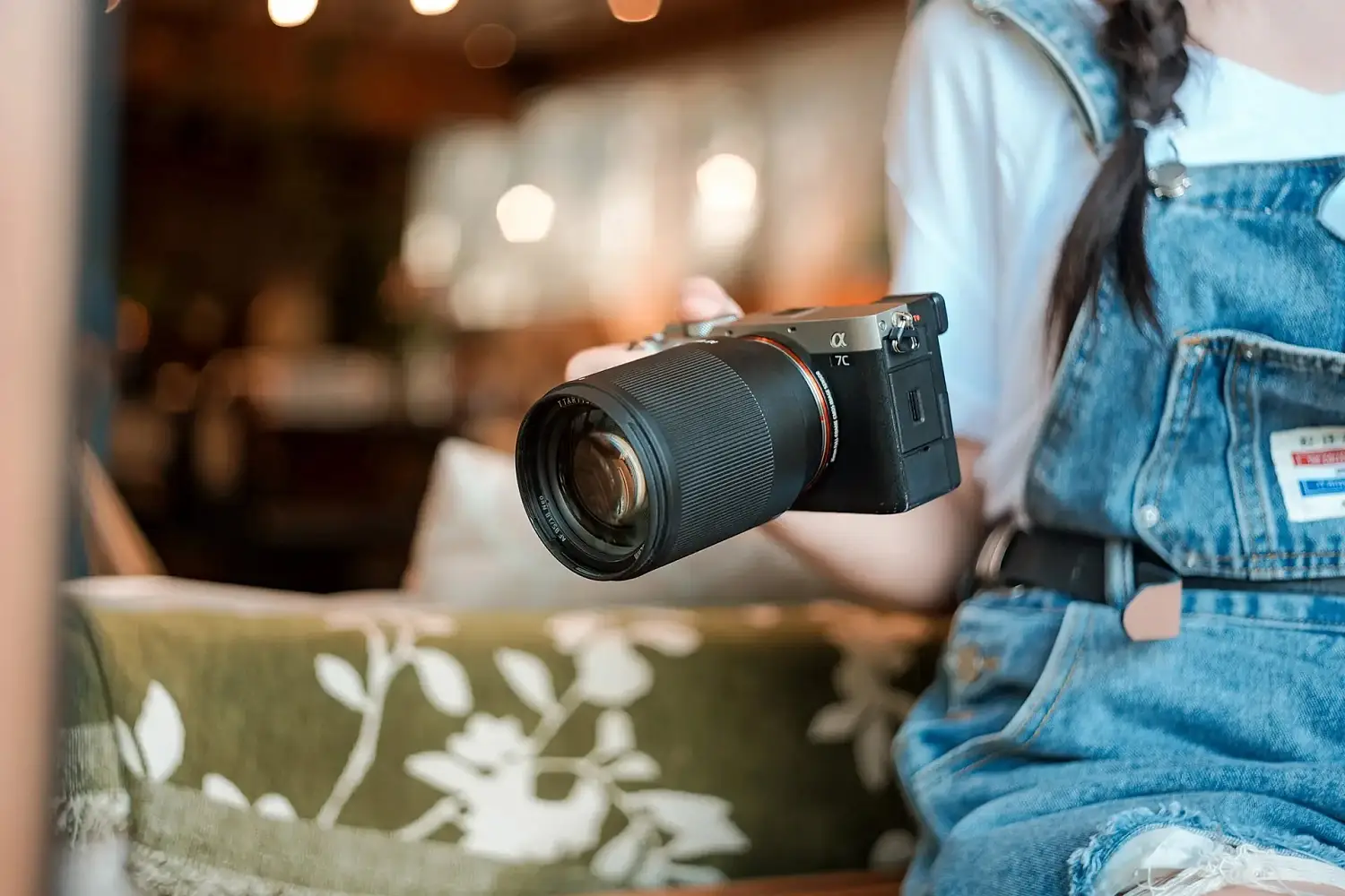 Камера Sony с объективом TTArtisan AF 85 мм F1.8 Neo в руках фотографа в кафе