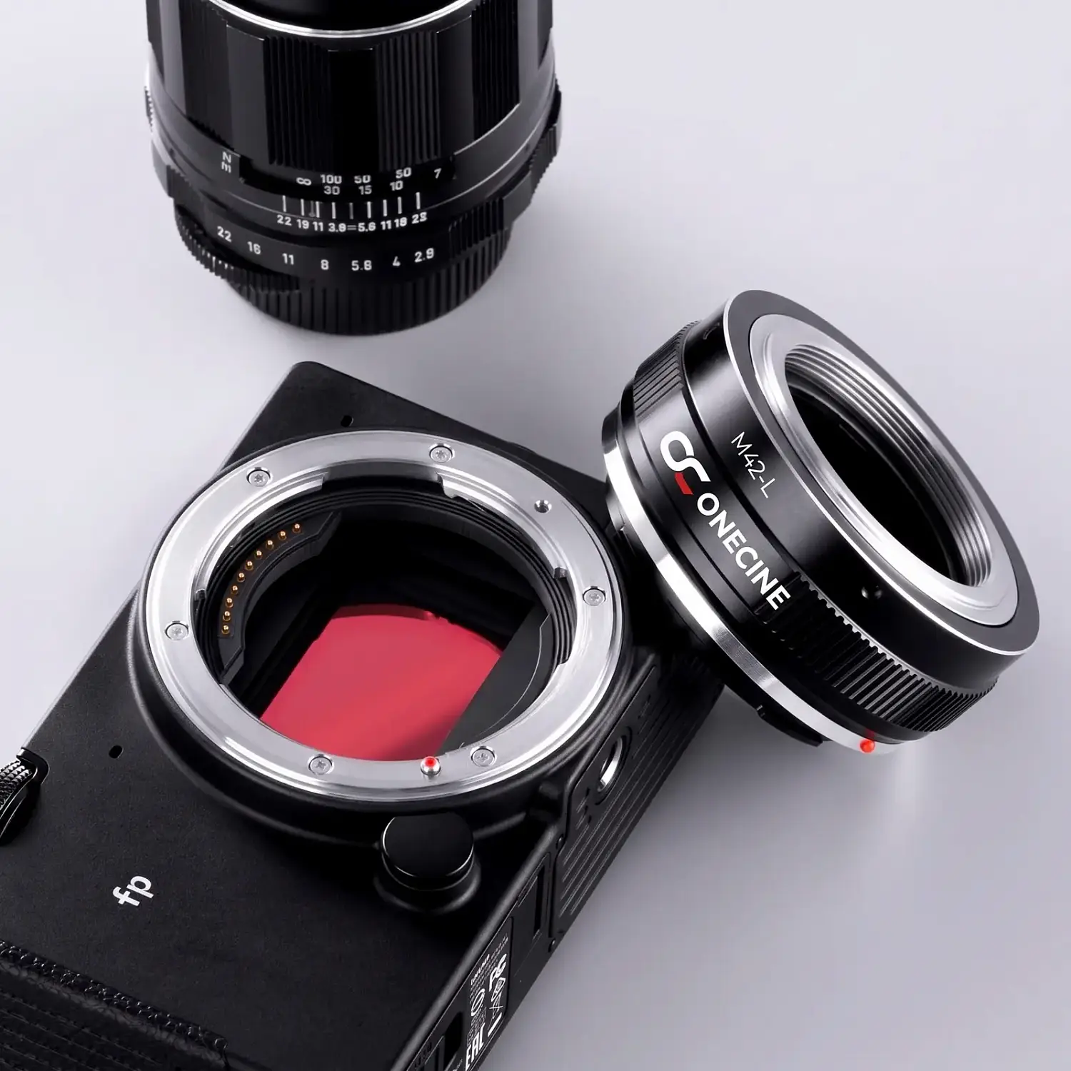 Переходное кольцо OneCine M42-L рядом с байонетом L-Mount камеры Sigma fp и объективом M42